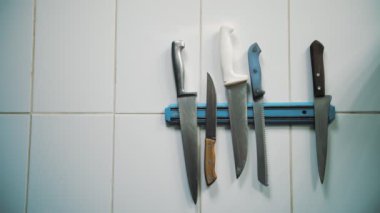 Mutfak bıçakları. Yakın plan. Bıçaklar manyetik bir tutucuda, fayans duvarında. Bıçakları olan manyetik tutucu