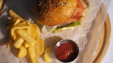 Hamburger. Yemek pişirmek. fast food. Yakın plan. Patates kızartmalı burger. Etli, sebzeli ve sahanda yumurtalı sulu burger. Patates kızartması ve domates sosuyla servis edilen hamburger. döndür.