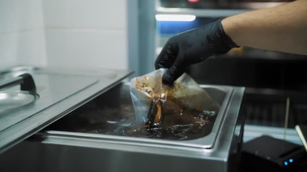 用Sous Vide技术在真空中烹调肉类 在餐馆里 手拿着排骨在一个特制的机器下 装在麻袋里 现代厨房的烹调 — 图库视频影像