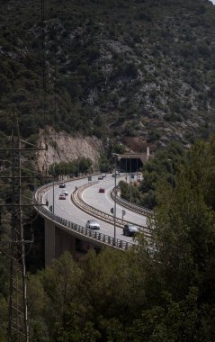 Dağların arkasındaki bir otoyolun üzerindeki köprü. Normal trafik