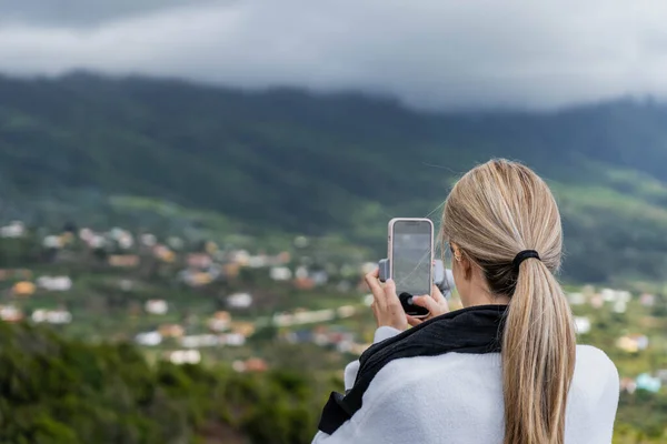 Doğası gereği akıllı telefonuyla köyde fotoğraf çeken beyaz bir kadın. 
