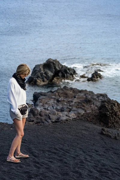 Woman Blonde Hair Sunglasses Looking Floor Black Sand Sea — Stock Photo, Image