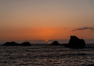 Gün batımında gökyüzü ve bulutların arasında güneş olan sakin bir deniz. Suyun üzerindeki sakin manzara ve ufuk.