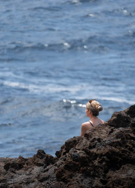 头发金黄的女人戴着太阳镜环视大海 沉重的岩石 — 图库照片
