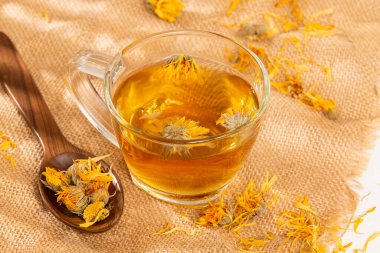 Bir fincan bitkisel çay kurutulmuş takvim ve kadife çiçeği.