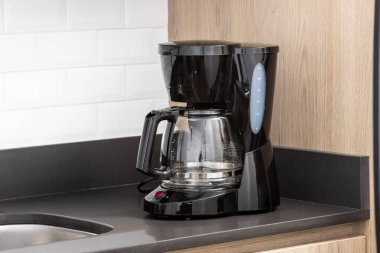 Mutfakta siyah bir elektrikli kahve makinesi var.