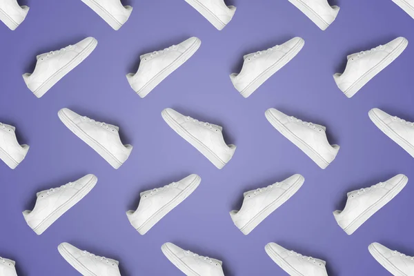 Pattern of white sneakers isolated on purple (Very Peri) background. Sportive pair of shoes for mockup. Fashionable stylish sports casual shoes. Modern and minimalist wallpaper of fashion lifestyle.