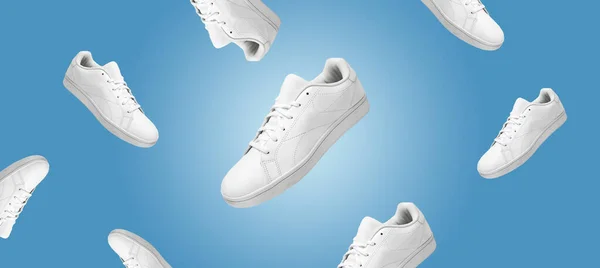 Banner with pattern of white sneakers isolated on blue background. Sportive pair of shoes for mockup. Fashionable stylish sports casual shoes. Modern and minimalist wallpaper of fashion lifestyle.