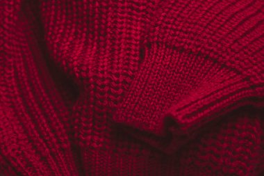 Kırmızı süveter dokusuna yakın çekim. Fotokopi alanı olan bir reklam arkaplanı. Sıcak, karamsar ve kışın giydiği süveterin kırmızı dokusu. 