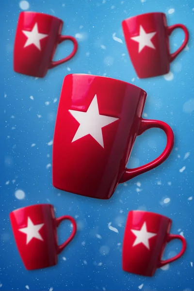Vertical image Christmas wallpaper with red mugs floating over blue and snowy background. Red Christmas mugs with blue snowy background. Christmas concept design.