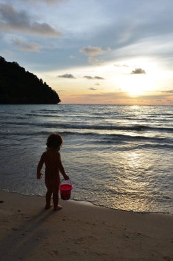 Tayland, Koh Kood Adası. Gün batımlı güzel bir atmosfer. Sıcak deniz, ahşap iskele, tatlı ve acı verici mutluluk hissi. Güzel günbatımı renkleri, batan güneşin aydınlattığı bulutlar. Denizde gün batımının yansıması.