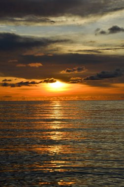 Tayland, Koh Kood Adası. Gün batımlı güzel bir atmosfer. Sıcak deniz, ahşap iskele, tatlı ve acı verici mutluluk hissi. Güzel günbatımı renkleri, batan güneşin aydınlattığı bulutlar. Denizde gün batımının yansıması.