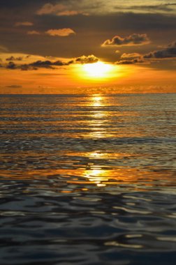 Tayland, Koh Kood Adası. Gün batımlı güzel bir atmosfer. Sıcak deniz, ahşap iskele, tatlı ve acı verici mutluluk hissi. Güzel günbatımı renkleri, batan güneşin aydınlattığı bulutlar. Denizde gün batımının yansıması.