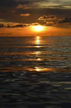 Tayland, Koh Kood Adası. Gün batımlı güzel bir atmosfer. Sıcak deniz, ahşap iskele, tatlı ve acı verici mutluluk hissi. Güzel günbatımı renkleri, batan güneşin aydınlattığı bulutlar. Denizde gün batımının yansıması.