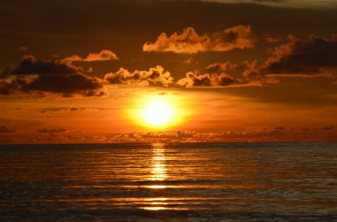 Tayland, Koh Kood Adası. Gün batımlı güzel bir atmosfer. Sıcak deniz, ahşap iskele, tatlı ve acı verici mutluluk hissi. Güzel günbatımı renkleri, batan güneşin aydınlattığı bulutlar. Denizde gün batımının yansıması.