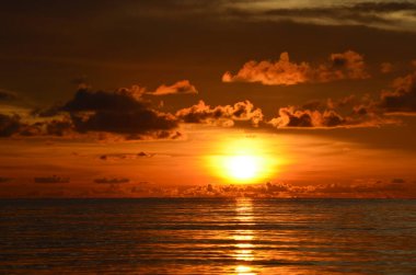 Tayland, Koh Kood Adası. Gün batımlı güzel bir atmosfer. Sıcak deniz, ahşap iskele, tatlı ve acı verici mutluluk hissi. Güzel günbatımı renkleri, batan güneşin aydınlattığı bulutlar. Denizde gün batımının yansıması.