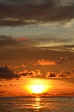 Tayland, Koh Kood Adası. Gün batımlı güzel bir atmosfer. Sıcak deniz, ahşap iskele, tatlı ve acı verici mutluluk hissi. Güzel günbatımı renkleri, batan güneşin aydınlattığı bulutlar. Denizde gün batımının yansıması.