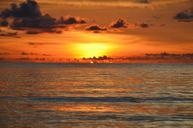 Tayland, Koh Kood Adası. Gün batımlı güzel bir atmosfer. Sıcak deniz, ahşap iskele, tatlı ve acı verici mutluluk hissi. Güzel günbatımı renkleri, batan güneşin aydınlattığı bulutlar. Denizde gün batımının yansıması.