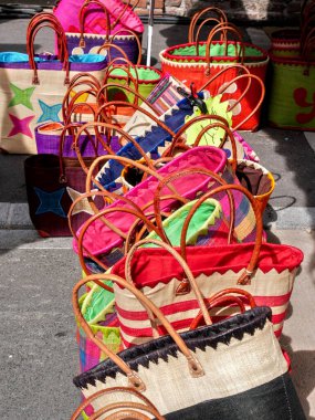 Çok renkli hasır çantalar, yere bırakılmış, bit pazarında satılıyor..