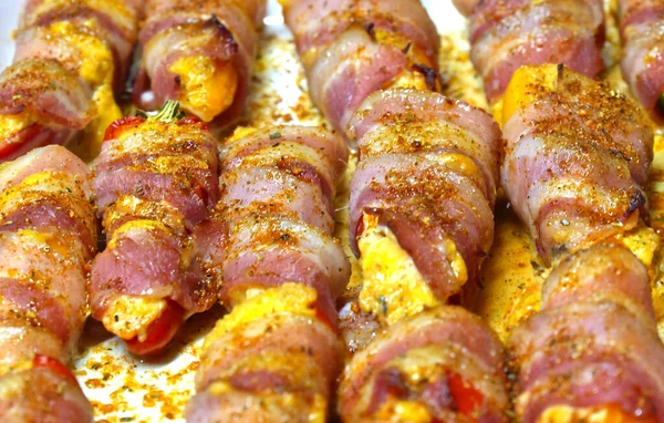 Preparation of a dish called Jalapeno poppers, composed of jalapeno peppers stuffed with cheese, sopasco and rolled with a slice of smoked bacon.