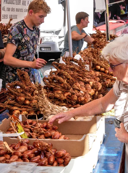 Arleux, Fransa - 09 04 2022: Yaşlı kadın Arleux 'daki sarımsak festivalinde tütsülenmiş arpacık soğanı almaya gitti.
