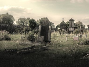 Eski terk edilmiş mezarlık. Eğimli mezarlar ve uzun otlar karanlık ve rahatsız edici bir atmosfer yaratır..