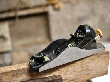 Kısmen bulanık küçük bir uçak, bir tahtaya yerleştirilmiş, bir ahlak zabıtası tarafından tutuluyor, bir marangozluk atölyesinde.