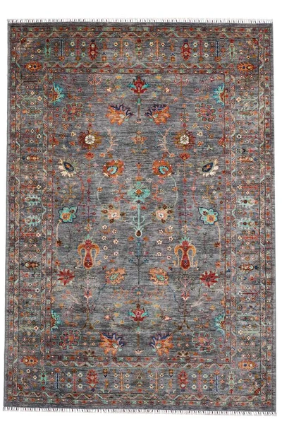 Arka planda el yapımı Afgan halısı var.