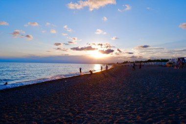 İnsanlar gün batımında deniz kenarında