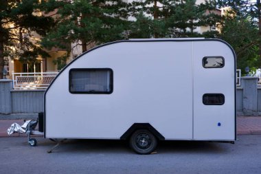 Beyaz karavan yol kenarında duruyor.