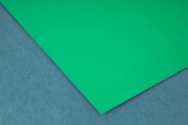 Plain green paper sheet lying on blue grey textured Background like an open book from top angle