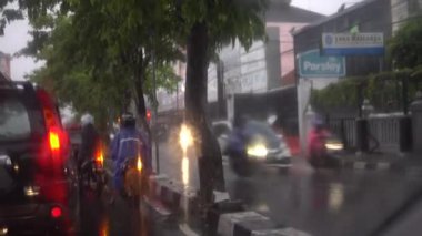 Trafik ışıklarının altında yağmur yağdığında otoyolun arkasındaki trafiği izliyorum.