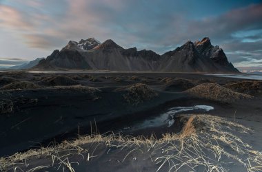 Stoksnes 'de arkasında dağlar olan siyah kum tepeleri