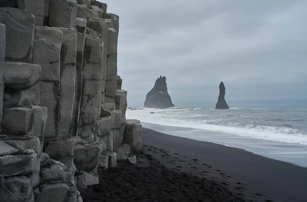 Rocks in the sea and basalt columns with black sand beach in Vk  Mrdal
