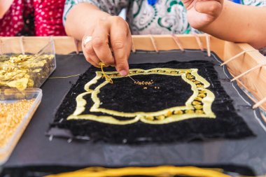 Panjakent, Sughd Eyaleti, Tacikistan. 18 Ağustos 2021. Sanatçı Panjakent 'teki Tarih Müzesi' nde geleneksel dikiş işi yapıyor..