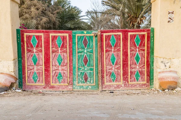 Faiyum, Egypt. Red and green painted wooden gate in a wall in the village of Faiyum.