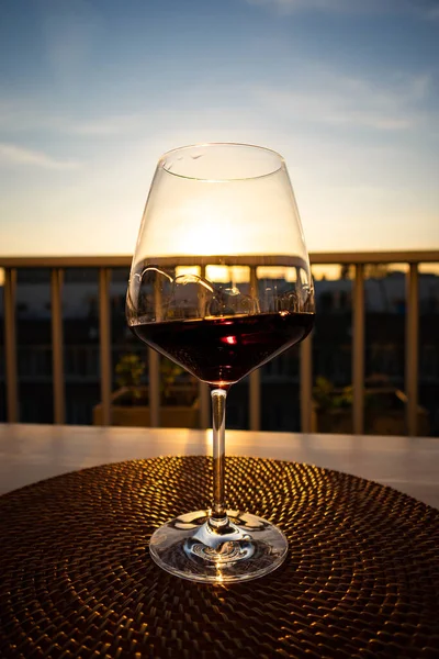 Glass of red wine in the evening sun. Burgundy style glass. Wine moving in the glass