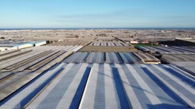 La Mojonera, Almeria, İspanya 'nın arka planında deniz ve beyaz köyle birlikte sera üzerinde yükselen drone ateşi. Su tüketim alanı. Yüksek kalite 4k görüntü