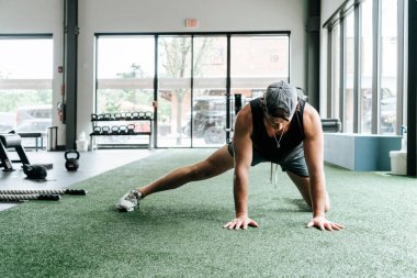 Formda ve motive olmuş genç bir erkek spor salonunda egzersiz yapıyor..