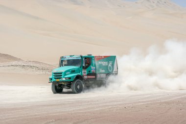 Dakar rallisinin arka planında çöldeki kamyonlar.