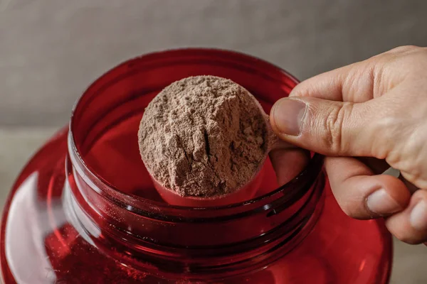 close up of a bowl of protein powder scoop with hand holding