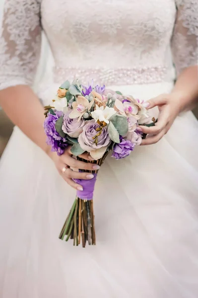Brides fees. Bouquet of the bride in her hands before the ceremony. High quality photo