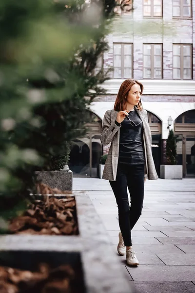 A girl in a business suit in the old town with glasses