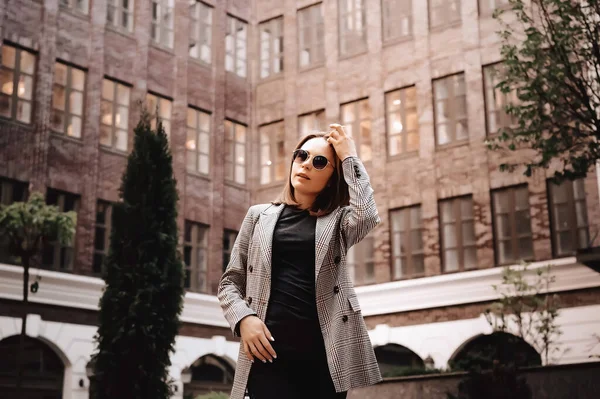 A girl in a business suit in the old town with glasses