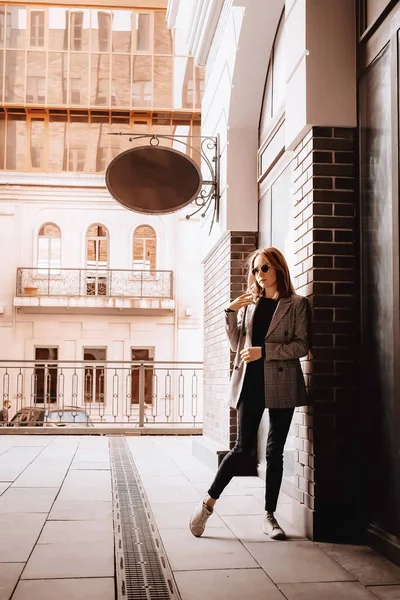 A girl in a business suit in the old town with glasses