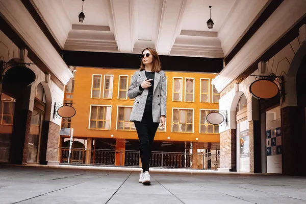 A girl in a business suit in the old town with glasses