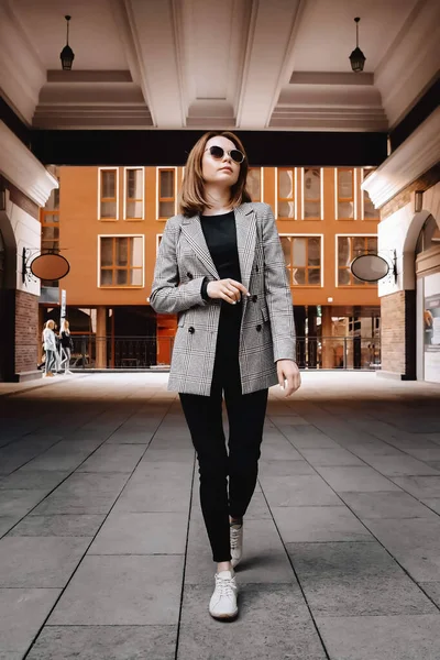 A girl in a business suit in the old town with glasses