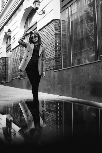 A girl in a business suit in the old town with glasses