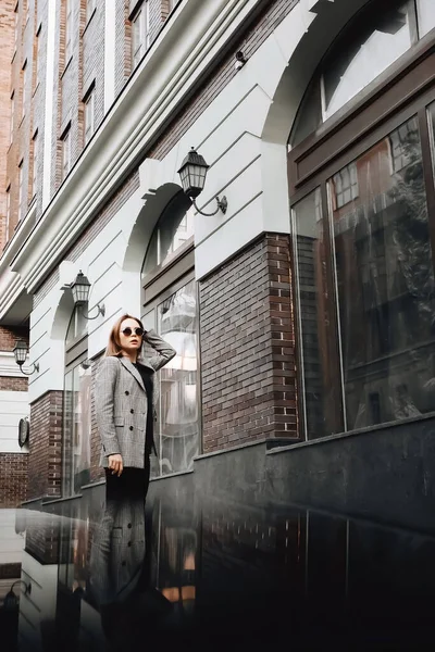 A girl in a business suit in the old town with glasses