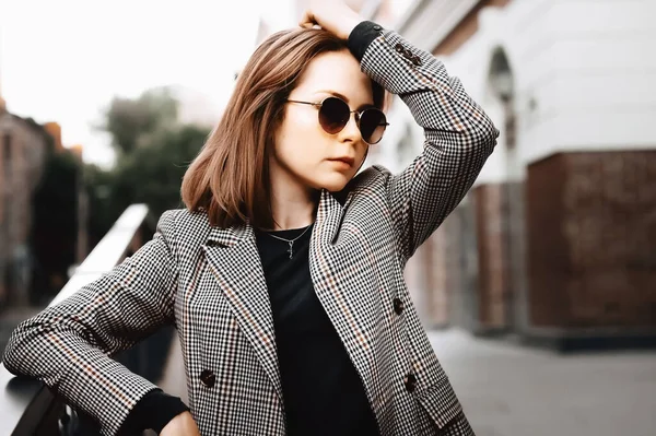 A girl in a business suit in the old town with glasses